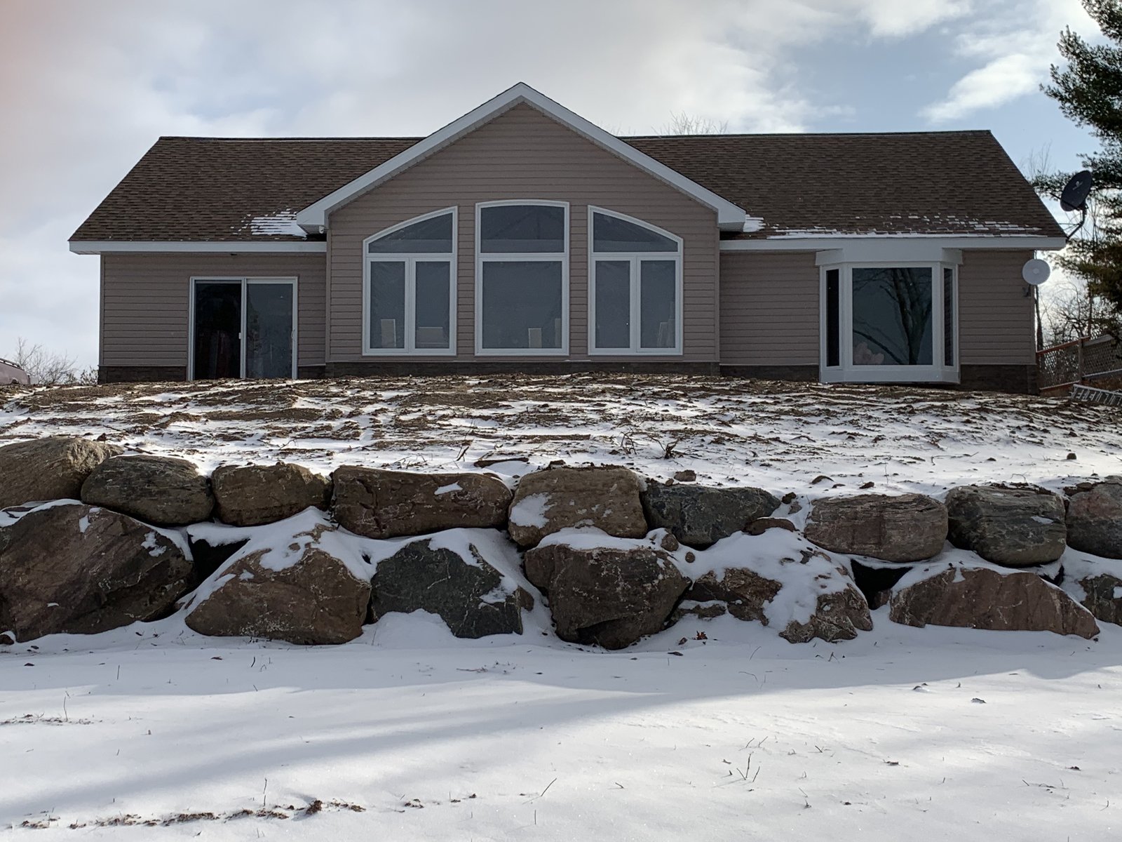 The finished home on a rock-walled waterfront lot, winter.