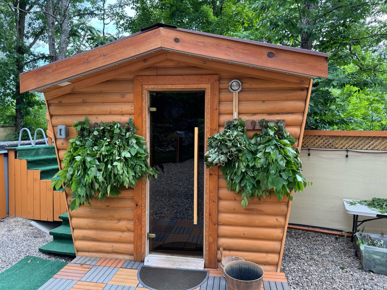 The finished cedar-lined mobile sauna in use, veniki hanging to dry by the door.